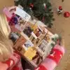 Kvinde i julesweater der åbner en låge i Aarhuskalenderen under juletræet