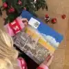 Kvinde i julesweater der åbner en låge i Frederikshavnkalenderen under juletræet