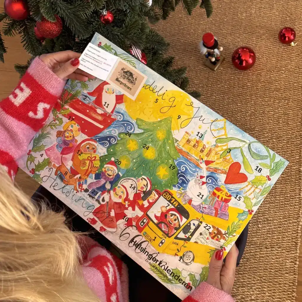 Kvinde i julesweater der åbner en låge i Helsingørkalenderen under juletræet