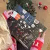 Kvinde i julesweater der åbner en låge i Odderkalenderen under juletræet